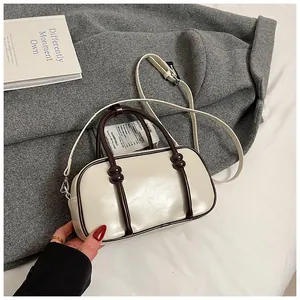 Détail du sac Boston crème avec poignées marron et bandoulière réglable texturée