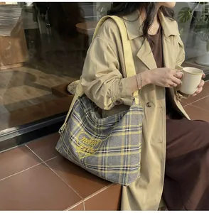 Detail of yellow plaid tote bag with heart embroidery on shoulder of model