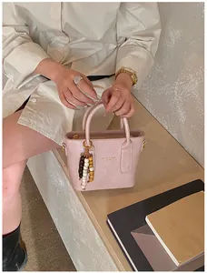 Detail der rosa Kunstleder-Eimertasche mit Modedruck und Perlenanhänger