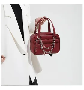 Detail of burgundy lychee leather handbag with metallic chains and heart charm