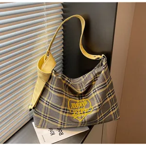 Detailed close-up of a plaid tote bag with yellow heart embroidery and stylish knot shoulder strap