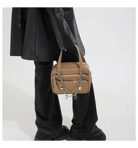 Detail of khaki briefcase featuring elegant silver multi-layer chains and heart charms
