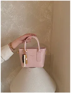 Detailansicht der rosa Handtasche aus Kunstleder mit Perlenquaste und Textaufdruck