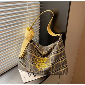 Detail of yellow heart embroidery on plaid tote bag with stylish leather knot strap