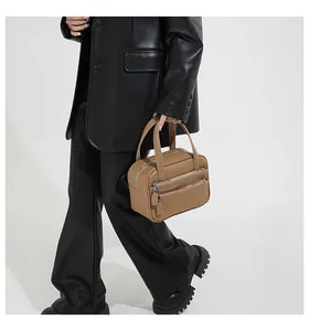 Close-up of caramel brown leather briefcase with stylish silver double zippers on the front