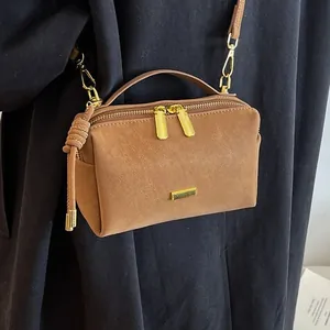 Vintage brown suede Boston pillow bag with gold hardware and tassel on black coat