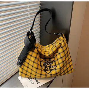 Detail of yellow and black checkered tote bag with heart embroidery and leather knotted strap