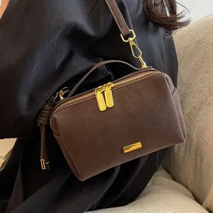 Minimalist brown matte leather Boston bag with gold zippers and crossbody strap