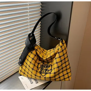Detail of yellow plaid canvas tote bag featuring heart embroidery and PU leather knotted strap