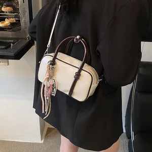 Sac Boston chic bicolore crème et café avec bandoulière longue et détail de gland