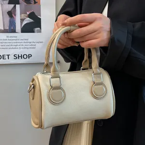 Bolso cilíndrico minimalista de lona con ribete beige, mostrado como accesorio elegante