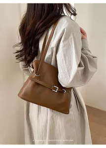 Detalle del bolso tote de cuero marrón caramelo con hebilla plateada en una modelo