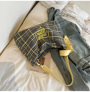 Detail of plaid tote bag featuring yellow heart embroidery and knotted leather strap