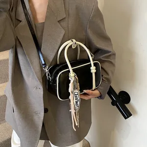 Sac Boston noir minimaliste avec liseré liseré blanc et breloque porté par un modèle
