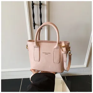 Detail der Textur der rosa PU-Leder-Eimertasche mit Tragegriffen und Schultergurt