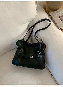 Detalle de bolso tote plisado negro minimalista con hebilla plateada y correas retro