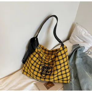 Detail of yellow and black checkered tote bag with leather strap and heart embroidery