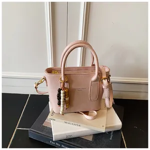 Detail der rosa Kunstledertasche mit Holzperlenanhänger und elegantem Markenlogo