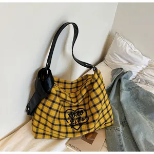 Close-up of plaid tote bag featuring heart embroidery and stylish leather knot detail