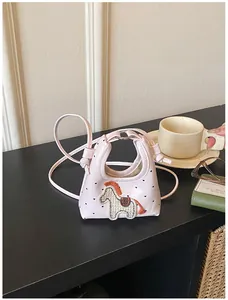 Dettaglio della mini borsa rosa con ricamo a cavallo e pois su un tavolo