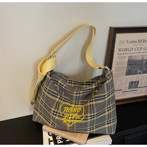 Detail of checkered shoulder bag with heart embroidery and yellow bow tied strap