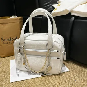 White lychee pattern leather briefcase with metal chains on a soft carpet setting