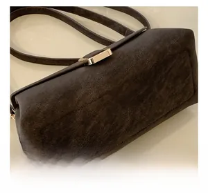 Close-up of the dark brown suede texture and golden square metal buckle on the crossbody bag