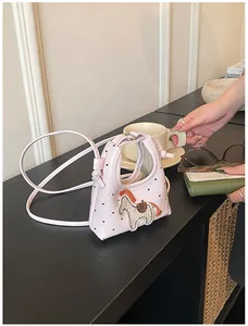Dettaglio mini borsa rosa chiaro con ricamo a cavallo e motivi a cuore su tavolo
