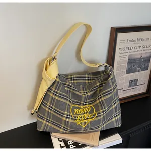 Close-up of plaid tote bag featuring heart embroidery and stylish decorative knotted strap