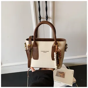 Nahaufnahme der zweifarbigen Ledertasche mit Perlenanhänger und Markenschriftzug