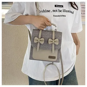 Detail view of stylish grey and beige canvas handbag with leather bows and a bear logo