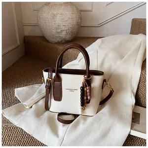 Detail der minimalistischen cremefarbenen Beuteltasche mit braunen Griffen und Holzperlen