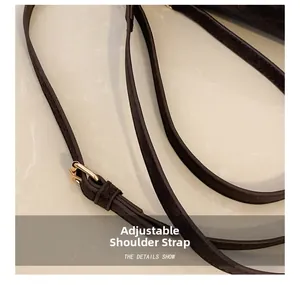 Detail of coffee brown suede shoulder strap with polished gold adjustable buckle
