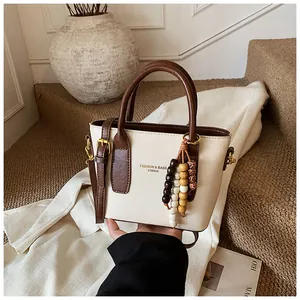 Detail der Retro-Beuteltasche in Creme und Braun mit bunter Holzperlen-Quaste und Gurt