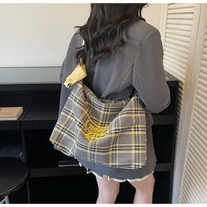 Detail of yellow plaid hobo bag featuring a heart embroidery and spacious canvas design