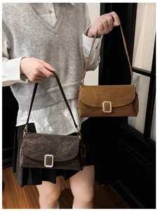 Detail of suede crossbody bags in dark coffee and caramel with gold buckles