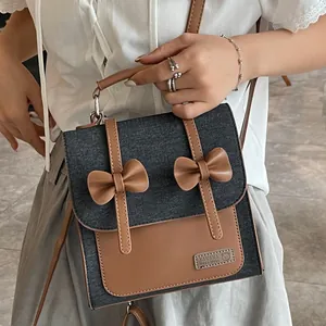 Vintage denim and brown leather patchwork handbag with two decorative bows and strap