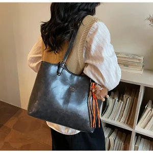 Détail du sac cabas noir vintage avec logo en métal et breloque en peluche sur la bandoulière