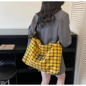 Close-up of yellow plaid tote bag with heart embroidery and black adjustable strap
