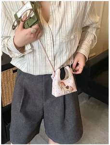 Dettaglio mini borsa rosa con ciondolo pony 3D e stampe a cuore sulla modella