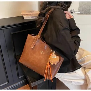 Detail view of retro brown tote bag with fuzzy monster charm and gold logo lettering