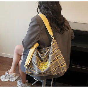 Detail of checkered tote bag featuring yellow heart embroidery and wide shoulder strap