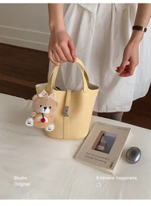 Detail van gele litchi lederen emmer tas met een schattige teddybeer hanger van pluche