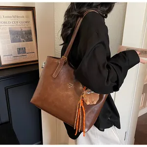 Detail of vintage brown tote bag with monster charm and orange tassel pendant