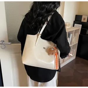Detail of off-white tote bag with metal logo, plush monster charm and orange tassel