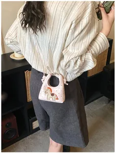 Dettaglio della mini borsa rosa con ricamo a cavallo indossata da modella in scena