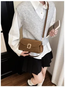 Detail of a brown rectangular crossbody bag with golden buckle on a casual outfit