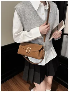 Brown rectangular crossbody bag with gold buckle on white shirt and grey knit vest outfit