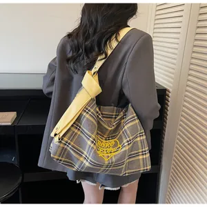 Detail of grey plaid canvas tote bag with yellow heart embroidery and wide shoulder strap