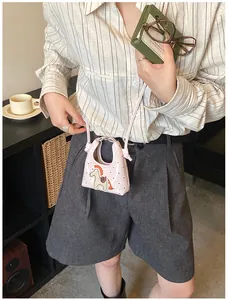 Dettaglio della mini borsa in vernice rosa con pony ricamato e motivi a cuore